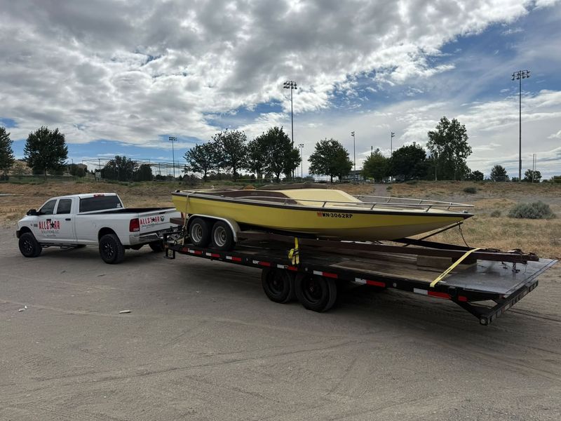 AllStarr Solutions truck towing a yellow powerboat away on a flatbed trailer
