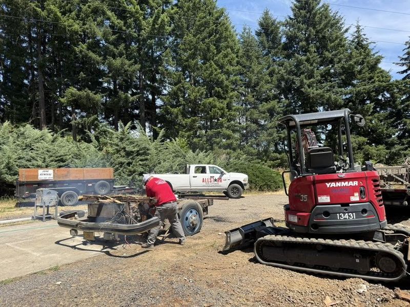 AllStarr Solutions crew member cutting up scrap metal beside a mini excavator and the company truck