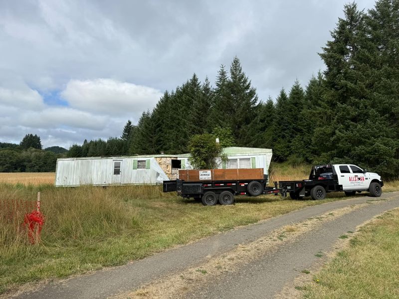 AllStarr Solutions truck and dump trailer parked at a derelict mobile home in a field