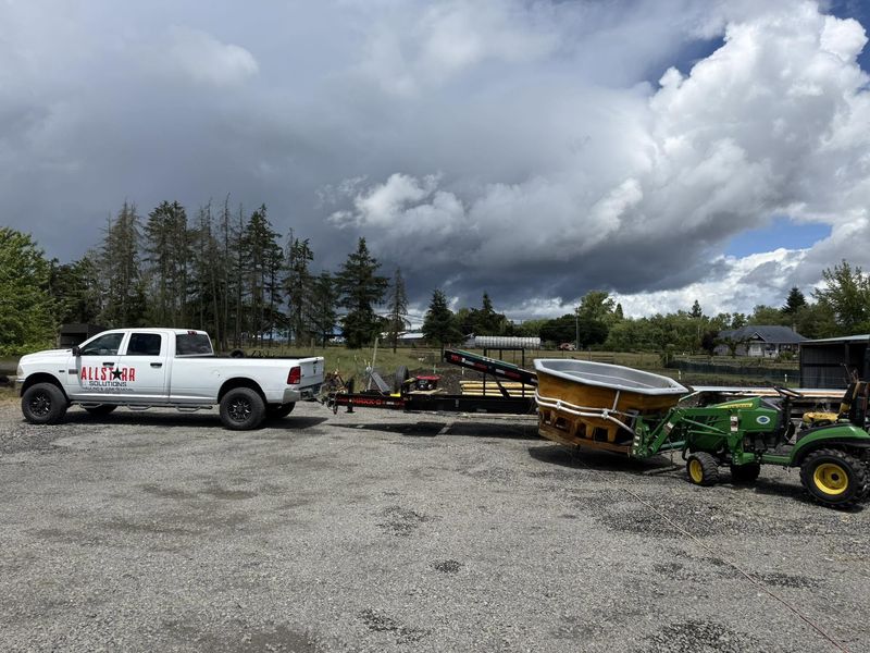 Hot tub carried on a tractor loader beside the AllStarr Solutions truck and trailer