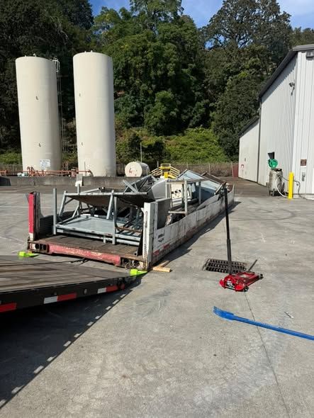 Industrial equipment strapped down on a flatbed trailer at a commercial site