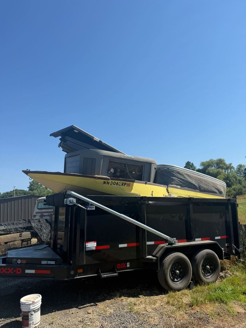 Sectioned boat hull and an old hot tub loaded together in a dump trailer for disposal