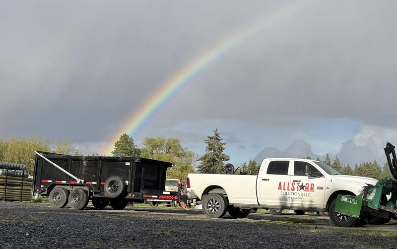 AllStarr Solutions pickup and dump trailer parked at the Newberg yard under a rainbow